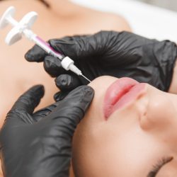 A cosmetologist makes lipolytic injections to burn fat on a woman's chin against a double chin. Women's aesthetic cosmetology in a beauty salon.The concept of cosmetology.