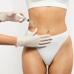 Close up of health care professional in gloves administering injection at belly of young european lady in white underwear. Health and medical treatment, weight loss, surgery and beauty care