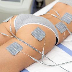 Beautiful woman getting electrostimulation therapy, anti-cellulite and anti-fat therapy on her tight buttocks in beauty salon