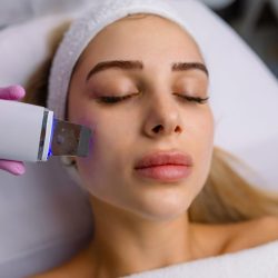 Facial cleansing with ultrasound scrubber. Woman receiving ultrasound facial peeling and cleansing. Cosmetology and face skin care. Facial treatment.