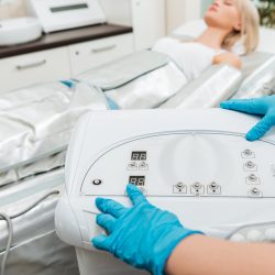 Cropped view of cosmetologist setting up machine for pressotherapy