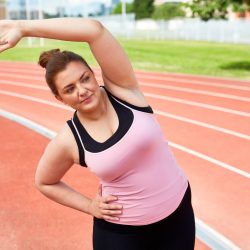 Young woman doing side-bends on stadium