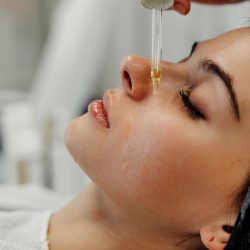 A woman enjoys a relaxing facial treatment with serum applied to her skin.